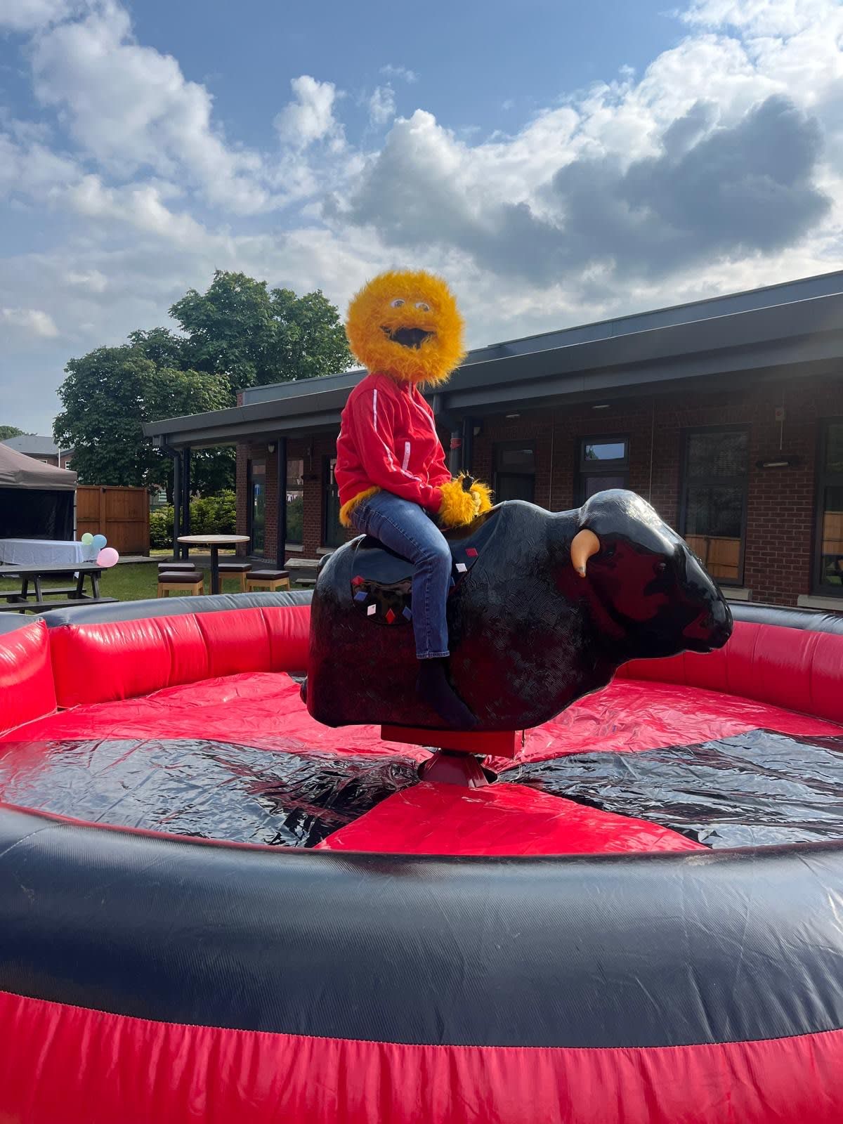 A rider in a mascot head on the bull at a corporate event