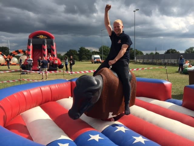 A rider smiling with one fist raised, holding on with the other hand