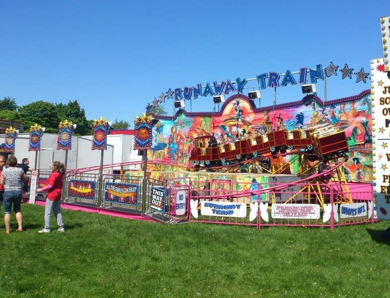 Chain of Runaway Train carriages climbing the elevated track section with riders aboard on grass