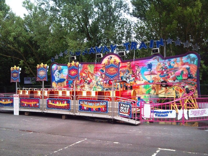 Front view of the Runaway Train on tarmac with star banners hung from the lettering arch and the ride entrance
