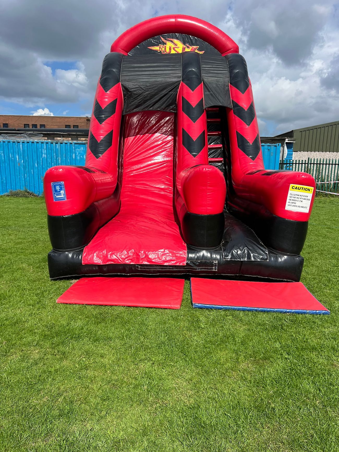 The large red and black slide standing on grass, showing its full scale