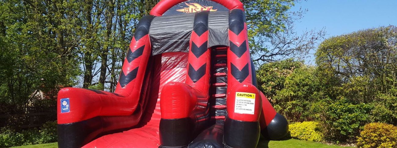 Rush Mega Slide inflatable set up outdoors, showing the red and black structure with its climb, arch and steep slide