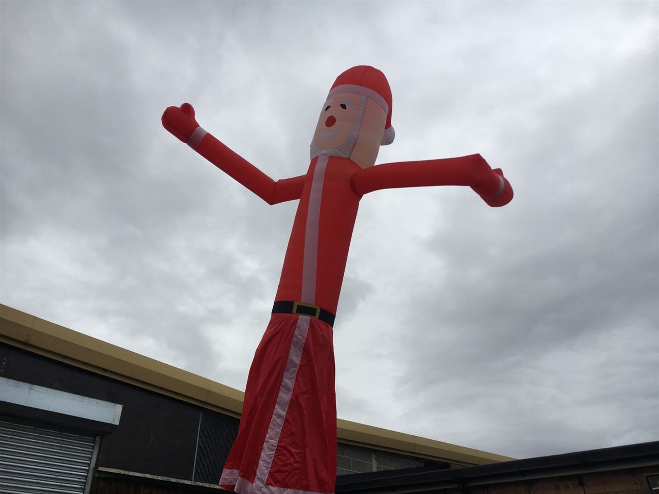 The Santa sky dancer with arms raised high against the sky, showing the printed facial details and white beard