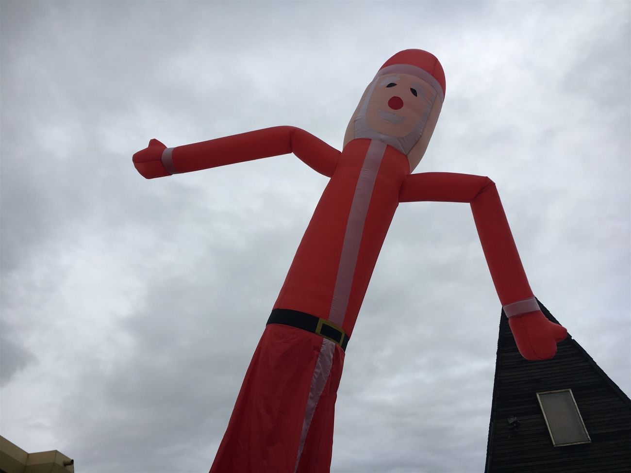 Low-angle view of the Santa sky dancer against the sky, showing the printed face and belt detail