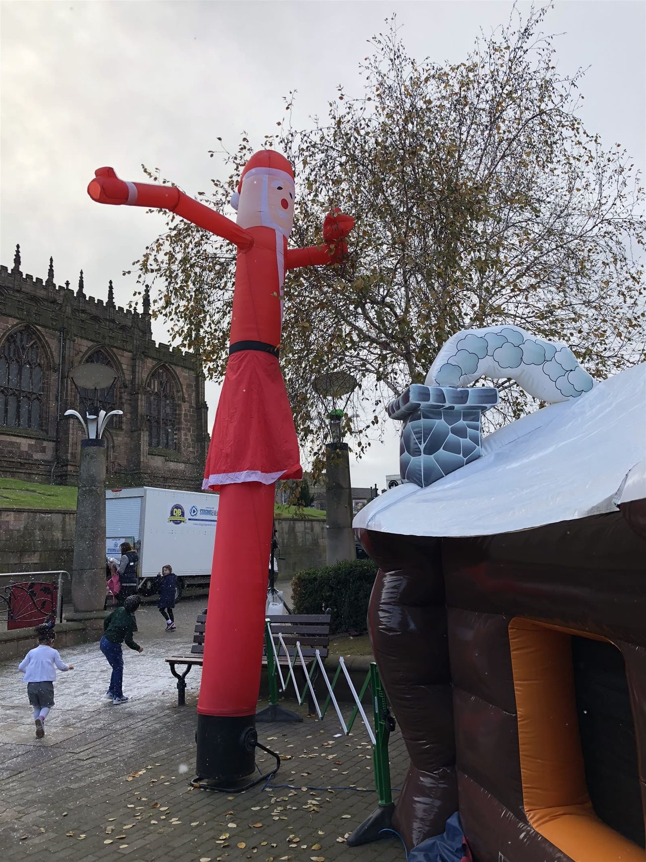 Wider town square view showing the Santa sky dancer, inflatable grotto and church behind