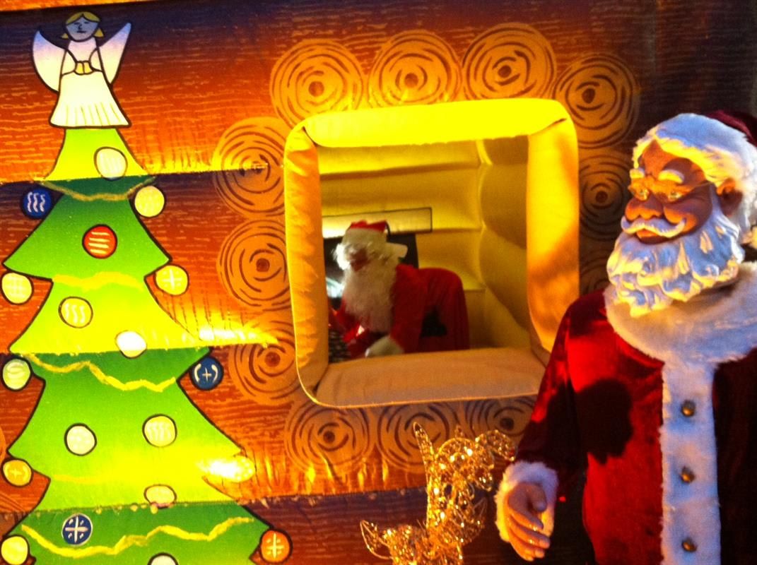 The exterior wall of the Santa's grotto, showing the printed Christmas tree and a freestanding Santa figure visible through the window