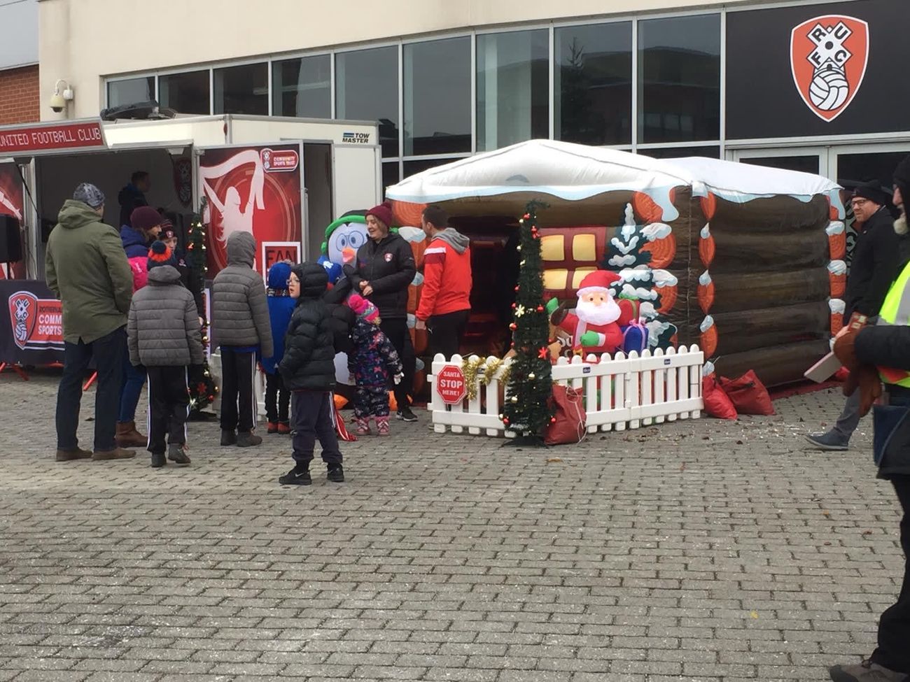 The Santa's grotto behind its garlanded picket fence, with an inflatable Santa and a queue of visitors