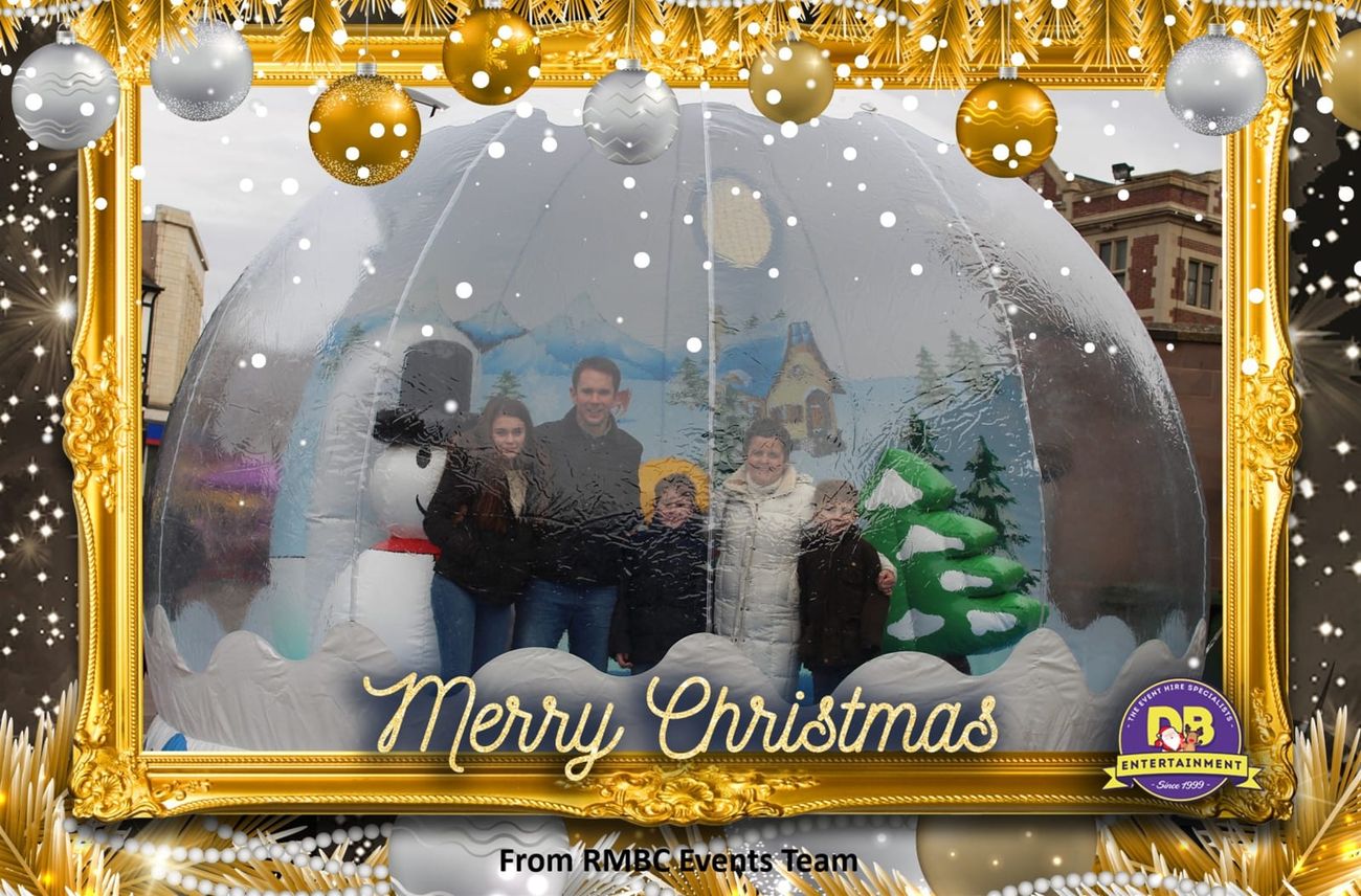 A family posing inside the snow globe pod, photographed through the clear dome
