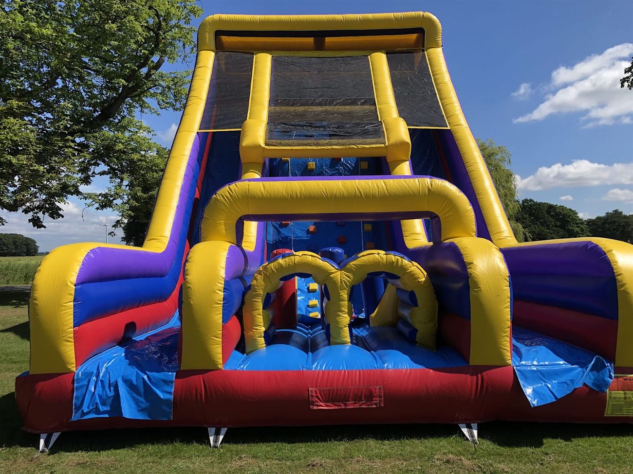The Tallest Mega Slide set up outdoors, showing the full multi-coloured obstacle course and slide structure