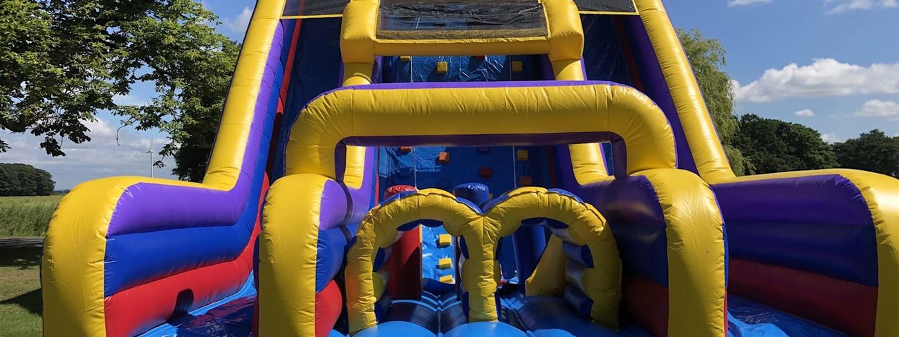 The Tallest Mega Slide set up outdoors, showing the full multi-coloured obstacle course and slide structure