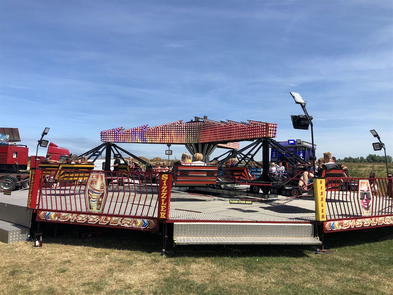 Full Twister platform in use with riders aboard, red perimeter fencing and central entrance steps