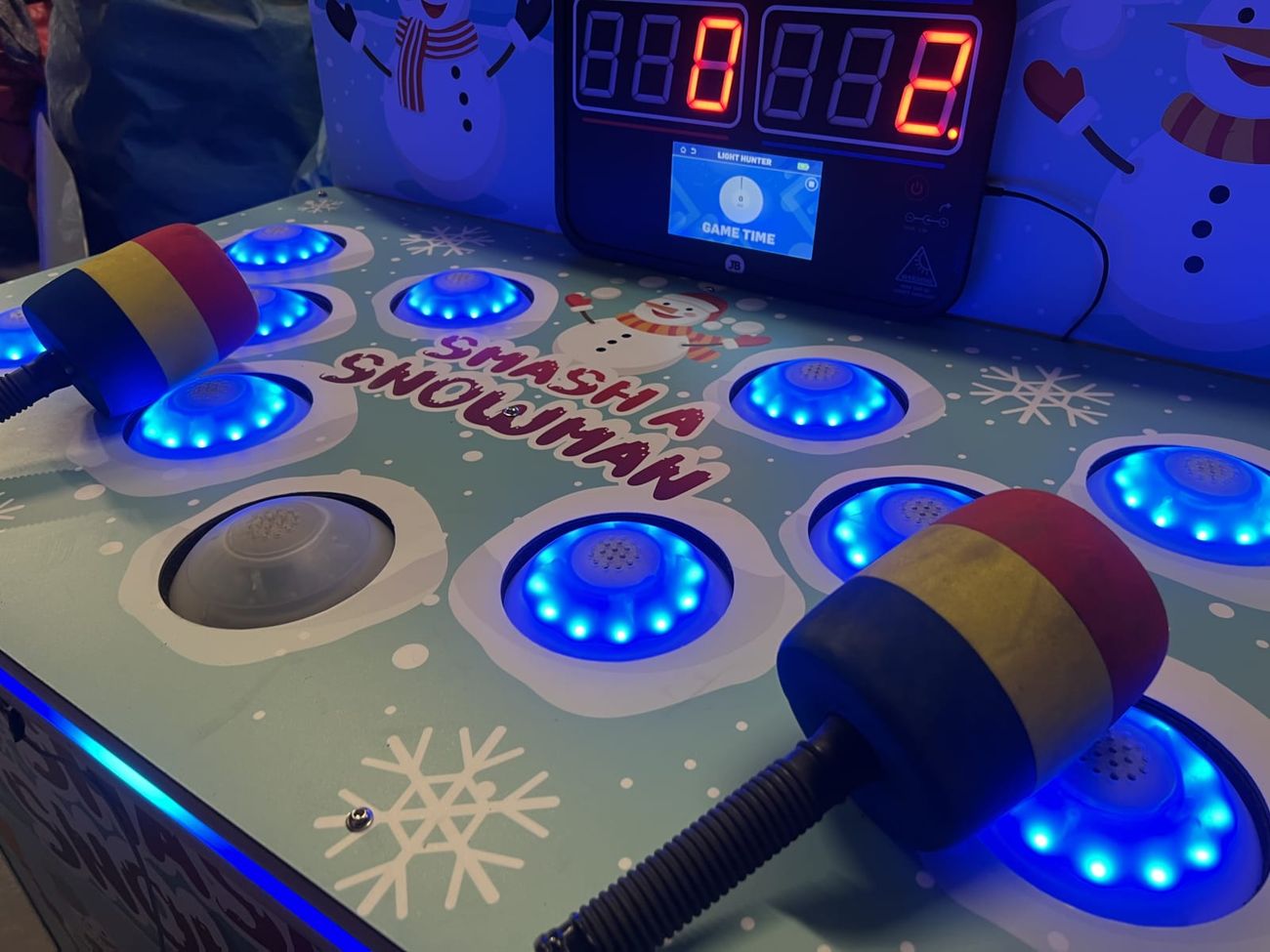 An angled view of the Whack a Snowman play surface with its glowing blue LED targets and foam mallets